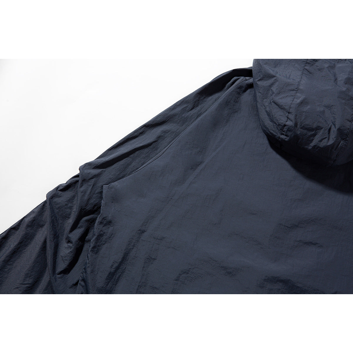 Close-up of the dark navy jacket’s hood and back fabric with visible seams and a crinkled surface.