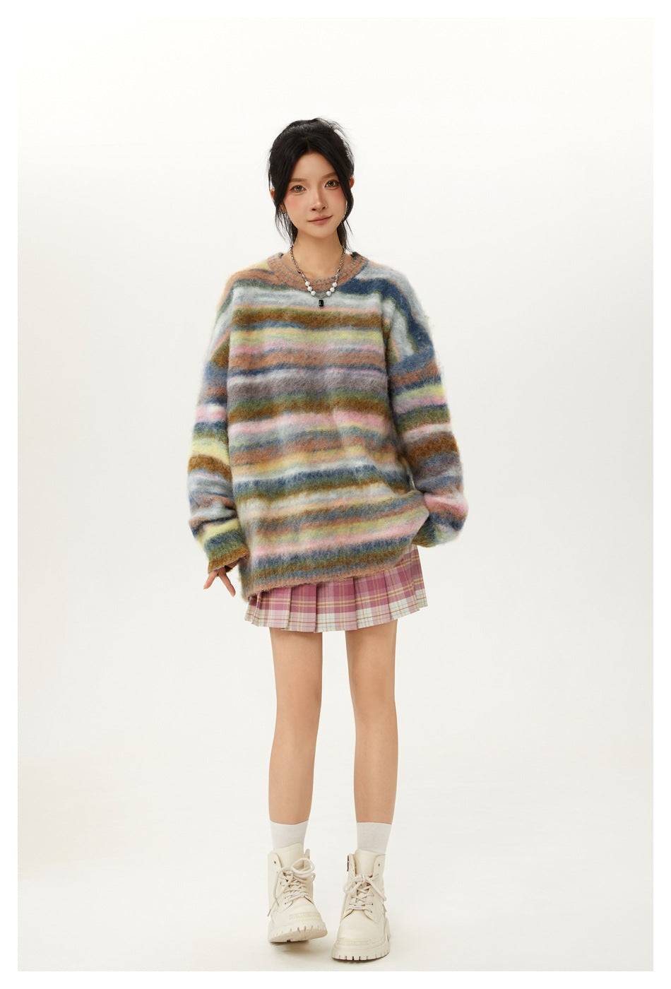 Model wearing a multicolor striped fuzzy sweater with a pink plaid pleated mini skirt and cream lace-up boots