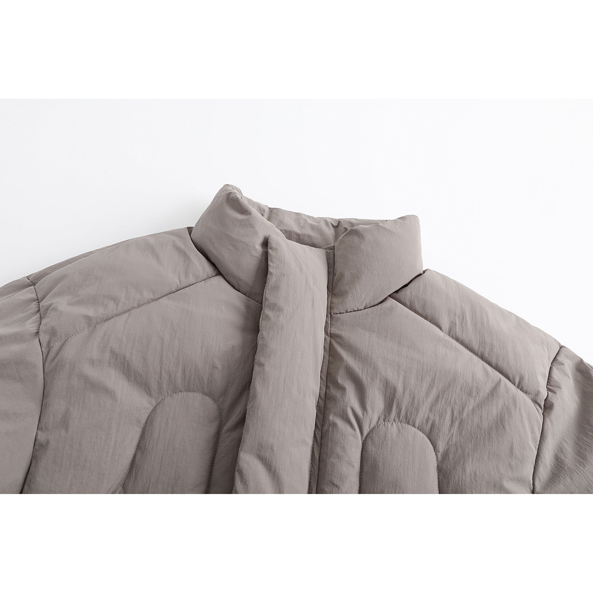 Close-up of a taupe padded jacket's high collar, front placket, and curved stitched panels.