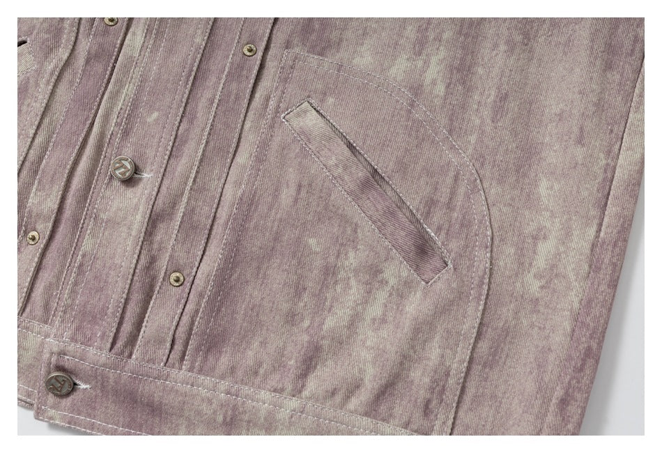 Close-up of a muted mauve, mottled jacket with a curved pocket, stitched panels and metal buttons.