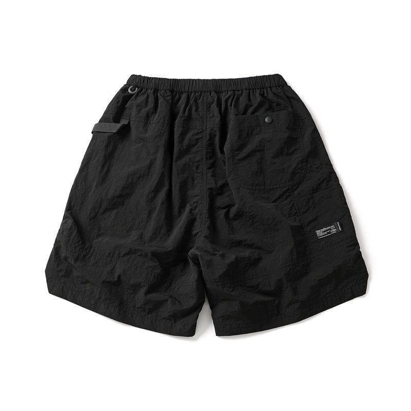 Black shorts shown from the back, with an elastic waist, single patch pocket, side tab and small leg label.