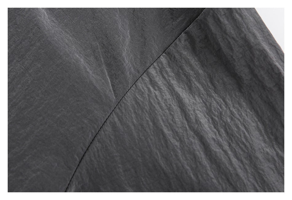 Close-up of a curved seam across the textured charcoal gray jacket fabric.