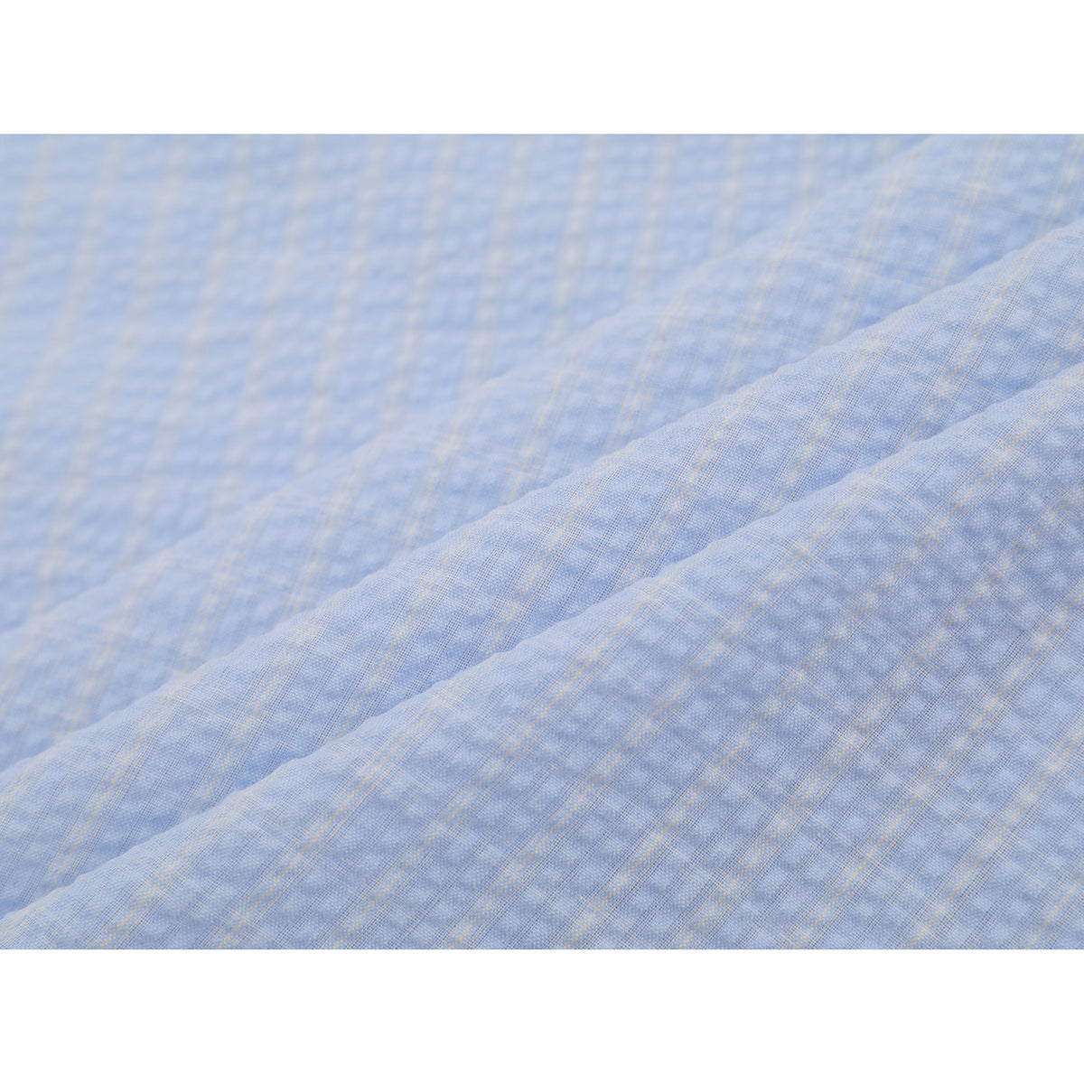 Close-up of the light blue shirt fabric, showing its fine woven texture and subtle plaid pattern.