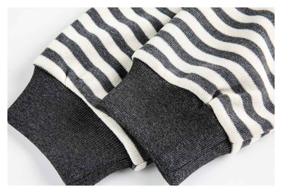 Close-up of two charcoal ribbed cuffs beneath cream and charcoal striped knit fabric.