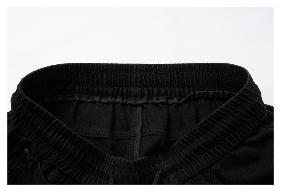 Close-up of the back waistband of black pants, showing elastic gathering and interior seams.