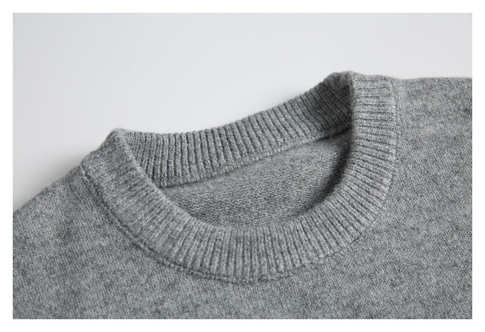 Close-up of a gray knit sweater's ribbed crew neckline and marled texture.