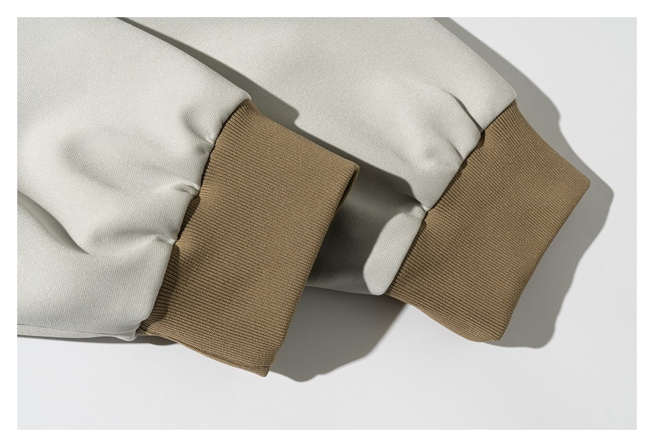 Close-up of cream jacket sleeves with wide tan ribbed cuffs.