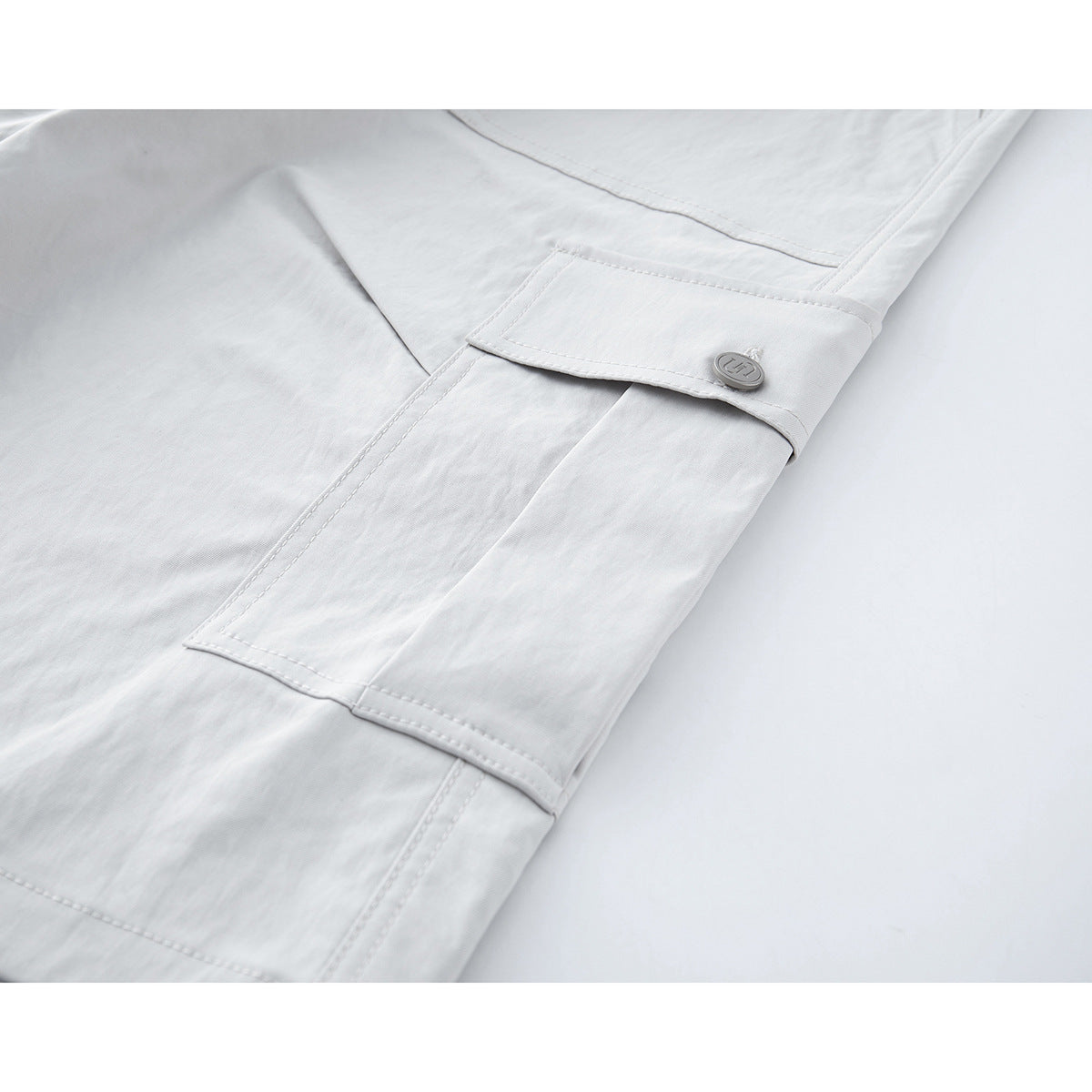 Close-up of white shorts showing a side cargo pocket with a buttoned flap.