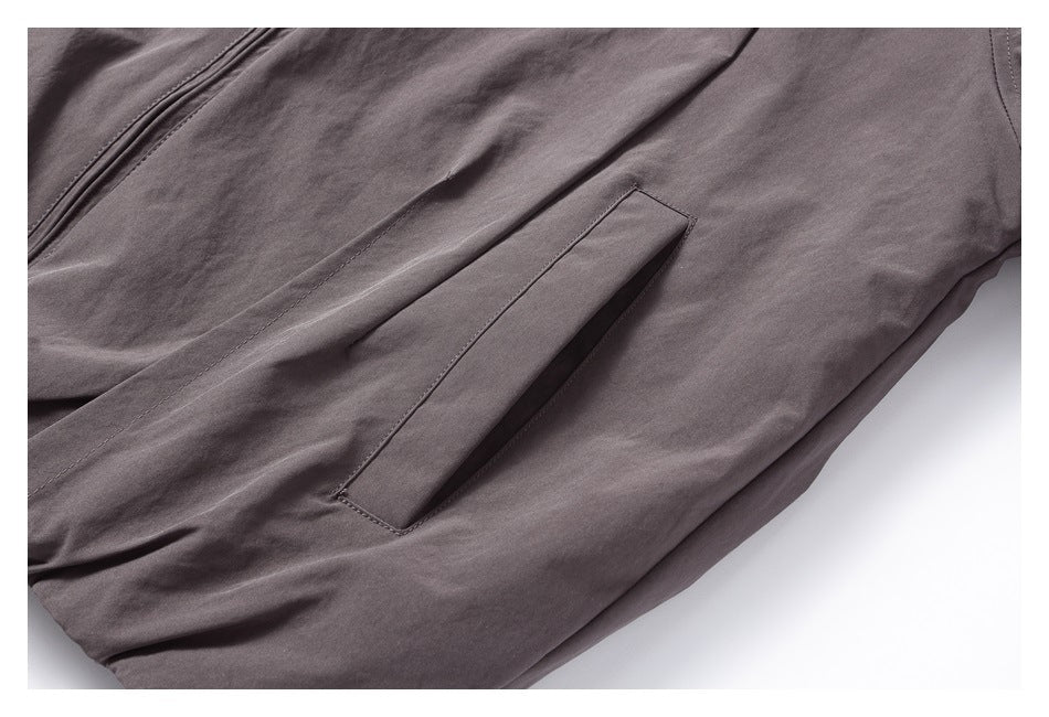 Close-up of a slanted welt pocket on a dark gray jacket.
