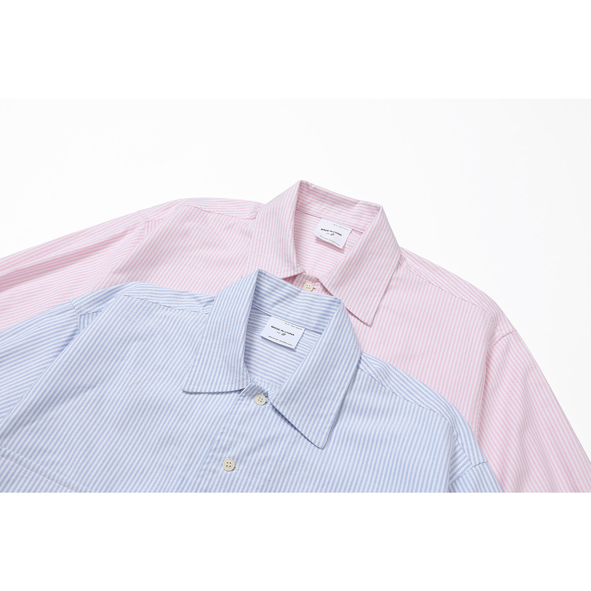 Close-up of overlapping pink and light blue pinstriped shirts, showing their pointed collars and buttons.
