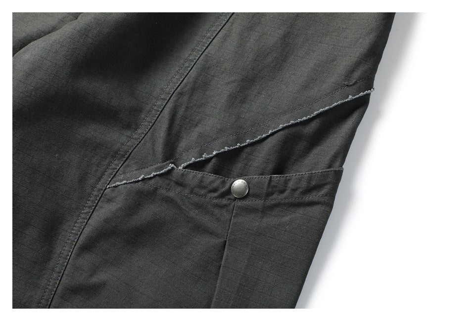 Close-up of a charcoal trouser pocket with a diagonal opening and small button.