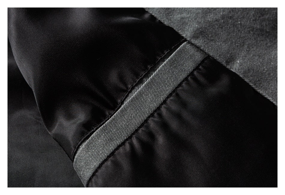 Close-up of black fabric with a wide gray woven band crossing diagonally between stitched sections.