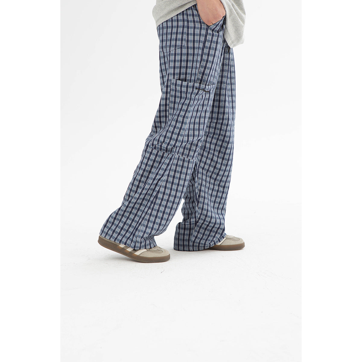 Model wearing loose blue and gray plaid cargo pants with a large side pocket and wide legs.
