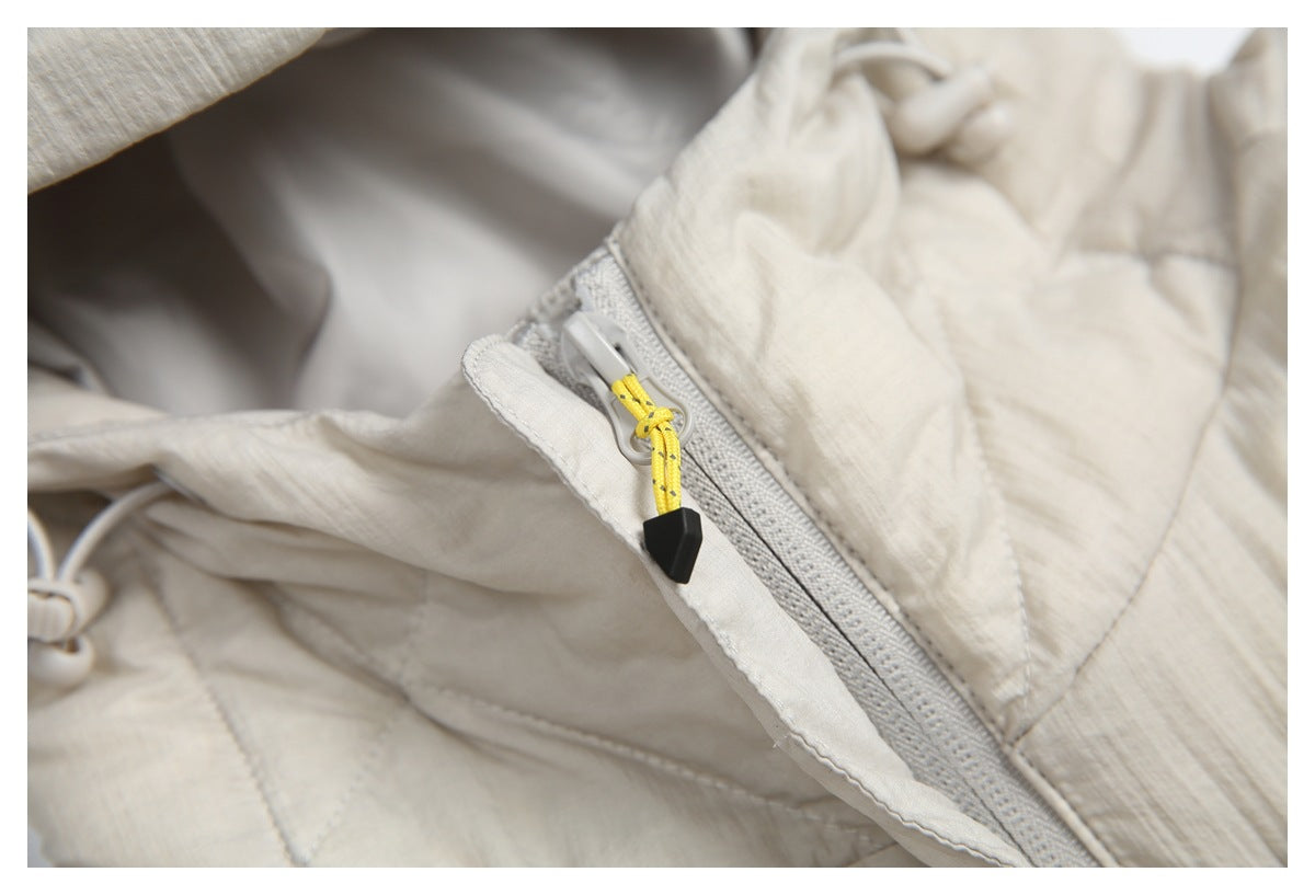 Close-up of a cream quilted jacket zipper with a yellow cord pull and black tip.