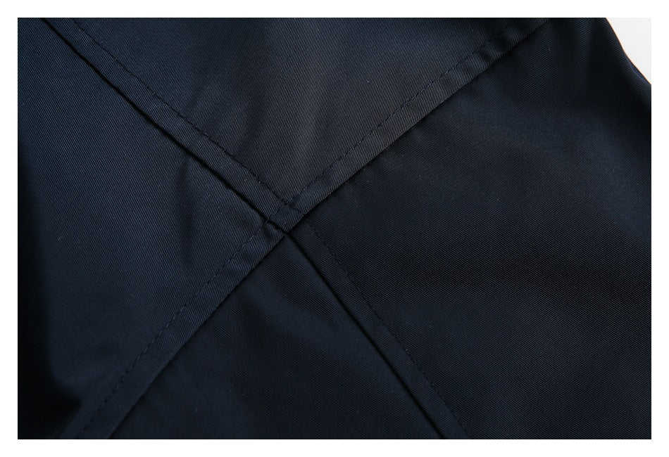 Close-up of intersecting stitched seams on dark navy fabric.