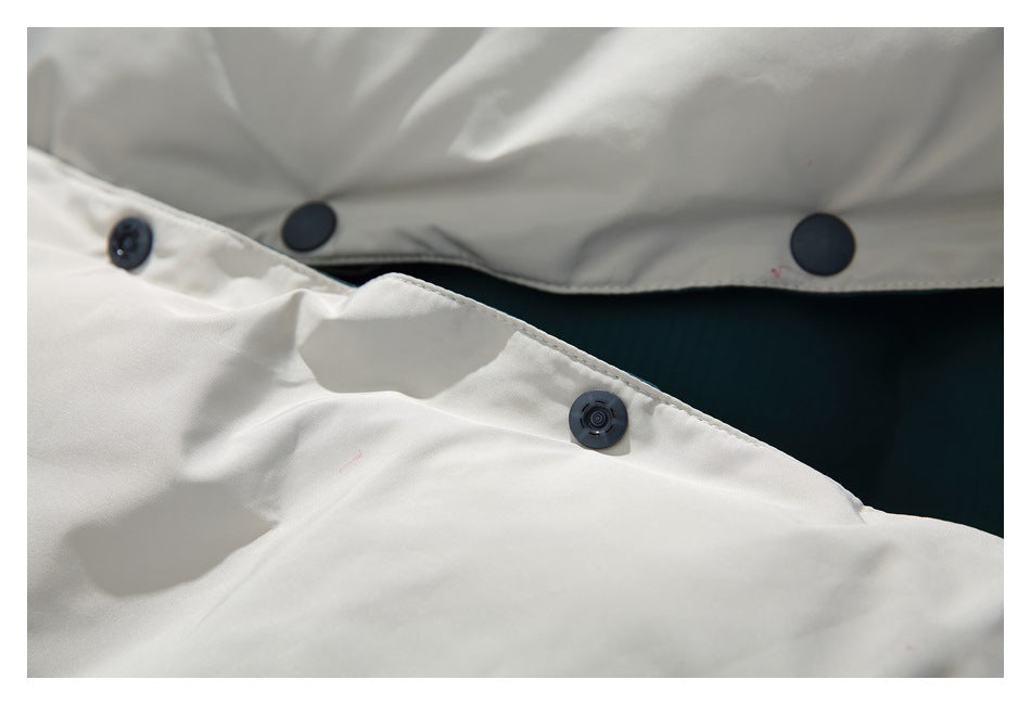 Close-up of dark snap fasteners joining white and dark teal sections of a garment.