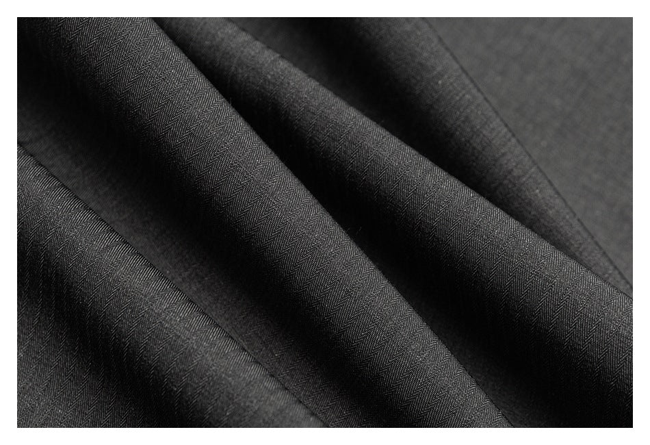 Close-up of dark charcoal fabric with a subtle herringbone pattern and soft folds.