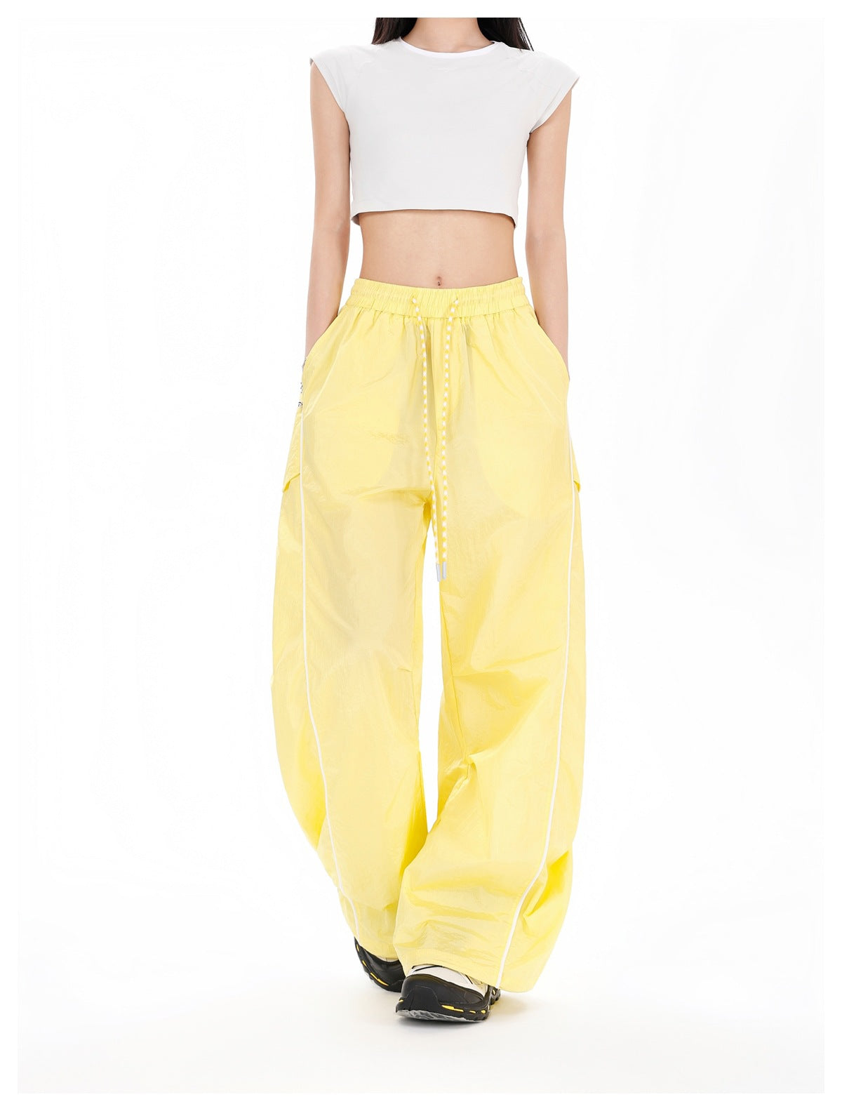 Model wearing yellow wide-leg pants with white piping, drawcord waist and a white cropped top, front view