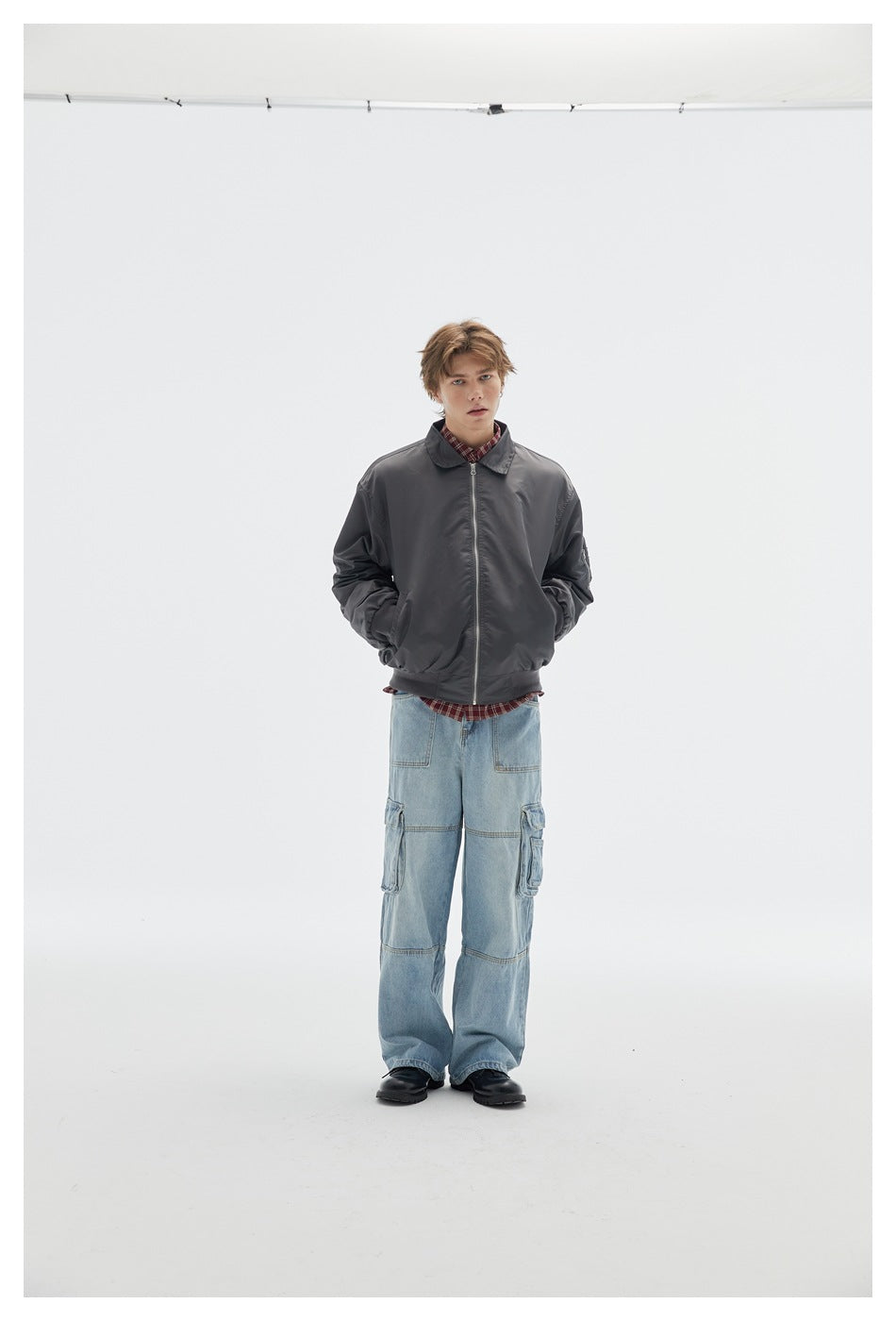 Front view of a model wearing a charcoal zip-front jacket with light blue cargo jeans.