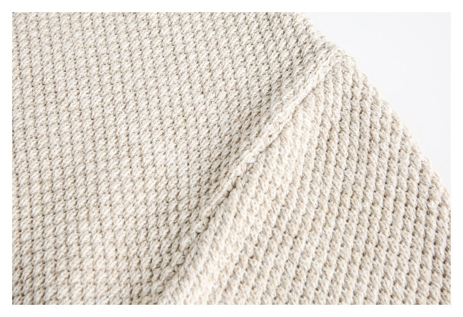 Close-up showing the textured knit and shoulder seam of a cream sweater.