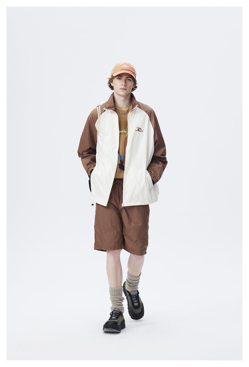Front view of a model wearing a cream-and-brown color-block zip jacket with matching brown shorts.
