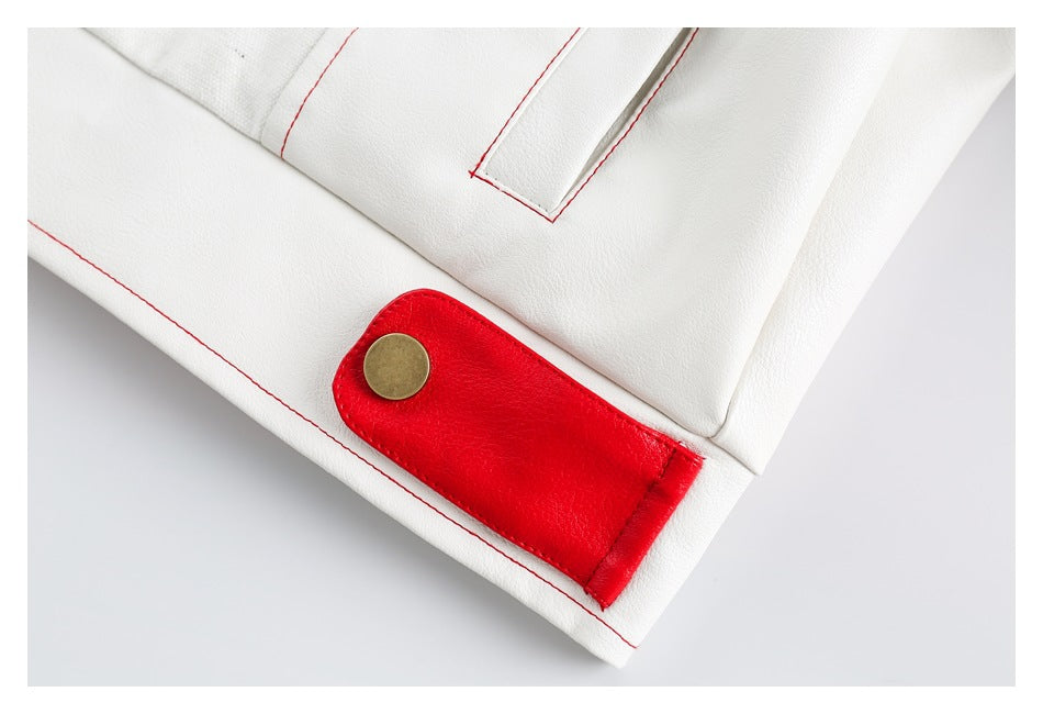 Close-up of a white garment with red stitching and a red tab fastened by a brass-colored snap.