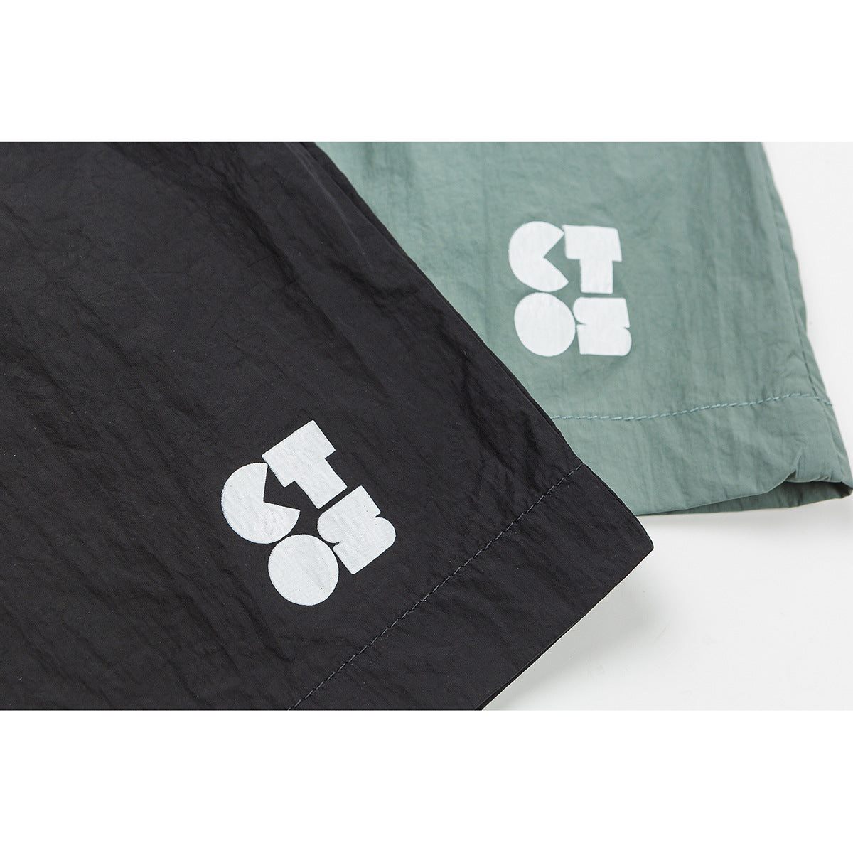 Close-up of black and sage green shorts hems with white geometric prints.