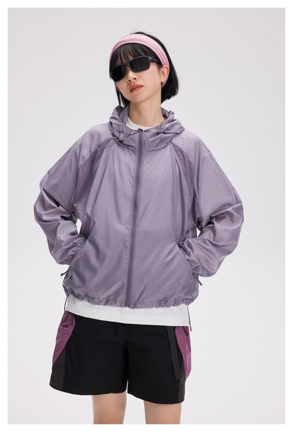 Woman modeling a lavender hooded zip-front jacket with contrast mesh panels and elastic cuffs.