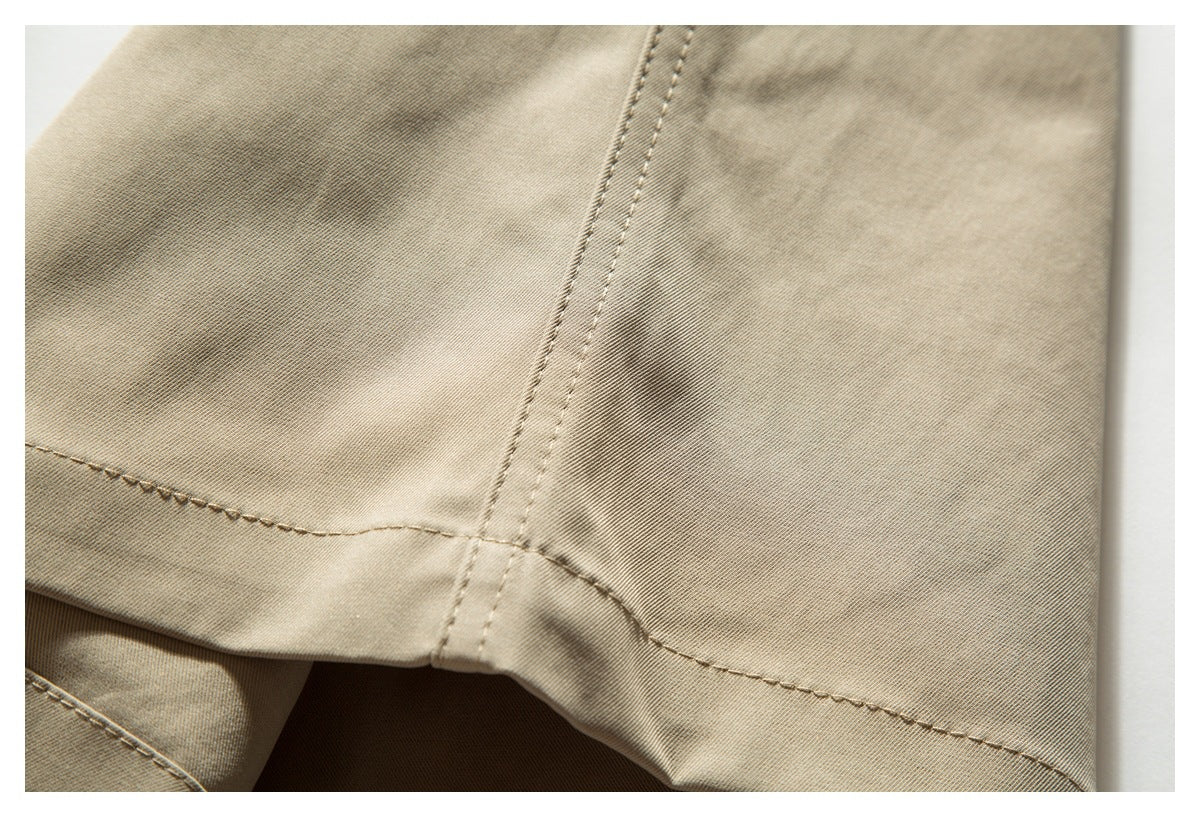 Close-up of light beige pants showing intersecting stitched seams and the folded hem.