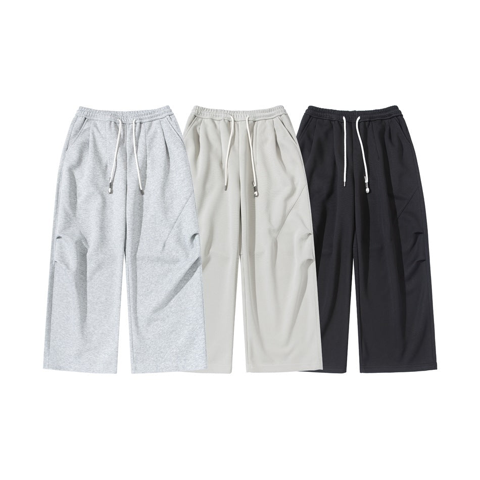 Three pairs of wide-leg drawstring sweatpants shown from the front in heather gray, off-white, and black.