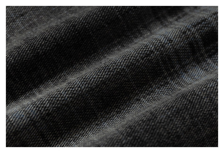 Macro view of dark, faded denim fabric with diagonal folds and a visible woven texture.