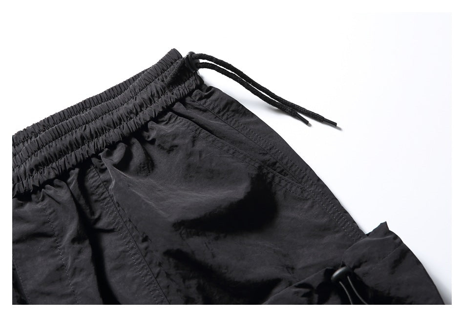 Close-up of the black shorts' elastic waistband, drawstring, and stitched pocket.