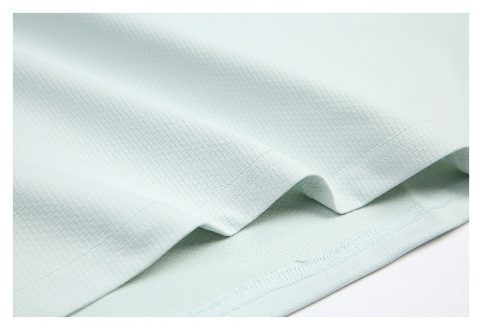 Close-up of the pale mint shirt's folded lower edge and stitched hem.