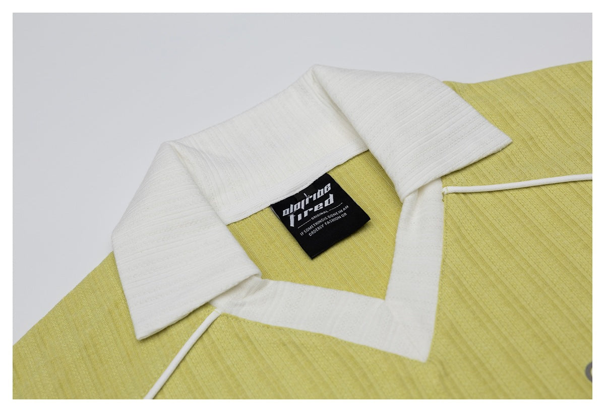 Close-up of a pale yellow shirt's white collar, placket, and black neck label.