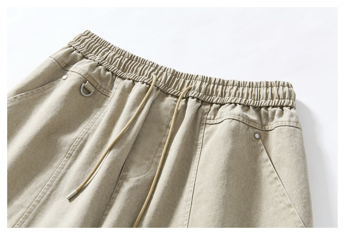 Close-up of light khaki bottoms with an elastic waistband, drawstrings, and angled pockets.