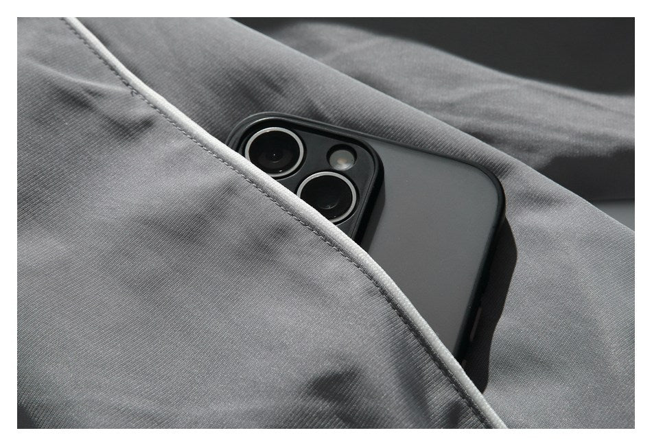 A smartphone tucked into a piped pocket on charcoal pants.