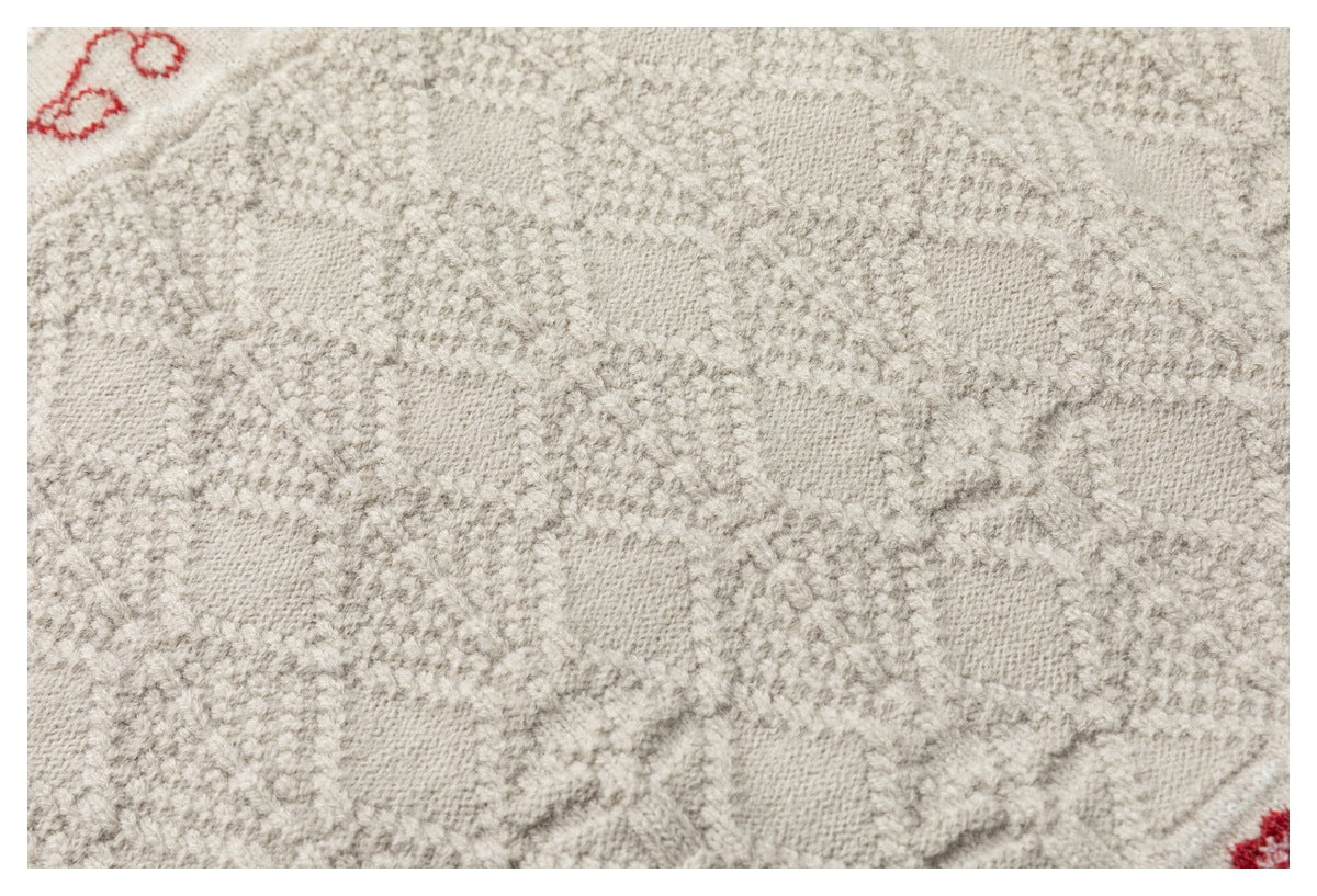 Close-up of the cream sweater's textured knit with a raised geometric pattern.