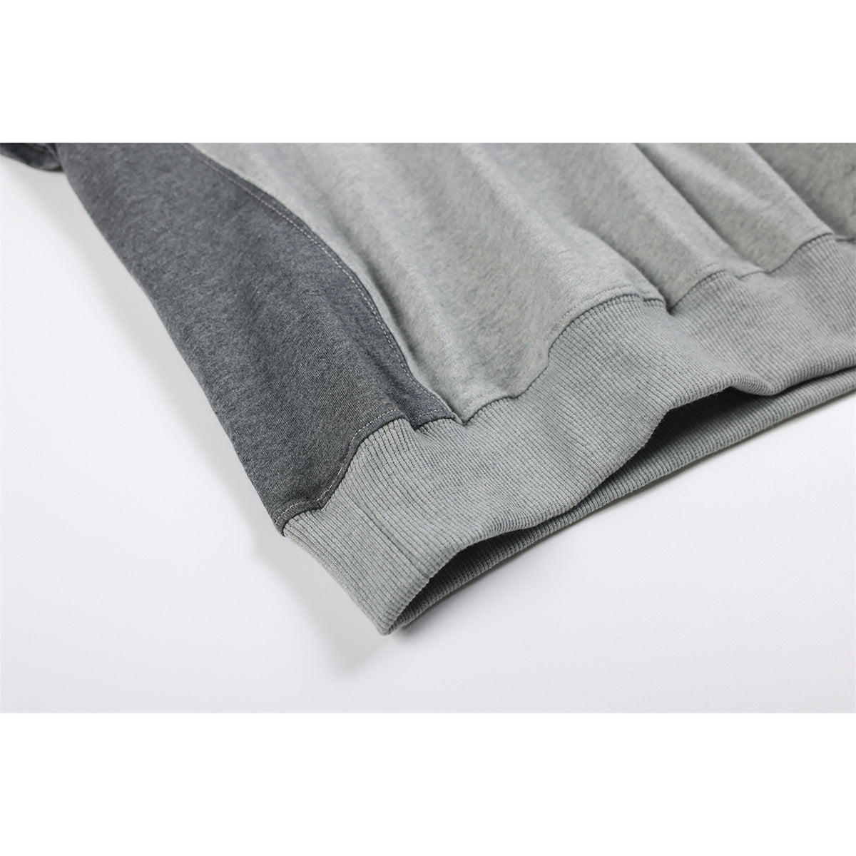 Close-up of a gray sweatshirt's ribbed hem and contrasting dark gray side panel.