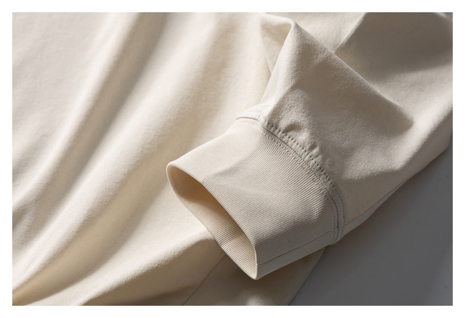 Close-up of a cream sweatshirt sleeve ending in a wide ribbed cuff.