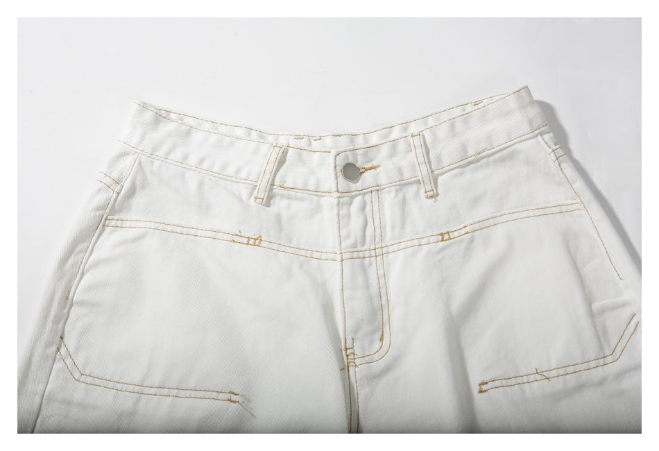 Close-up of the waistband, button, belt loops, fly, and contrast-stitched pockets on white shorts.