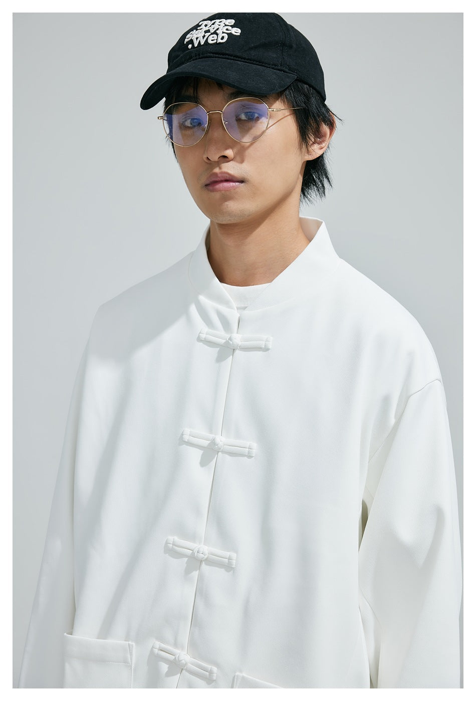 Upper-body view of a model wearing a white mandarin-collar jacket with white frog closures.