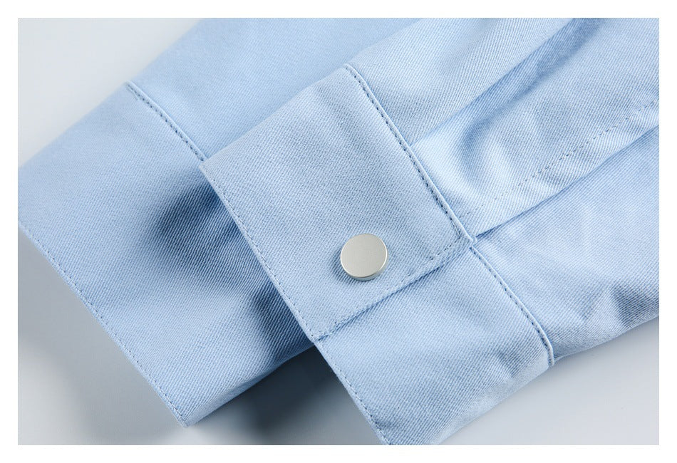Close-up of a light blue cuff with a round silver snap and visible stitching.