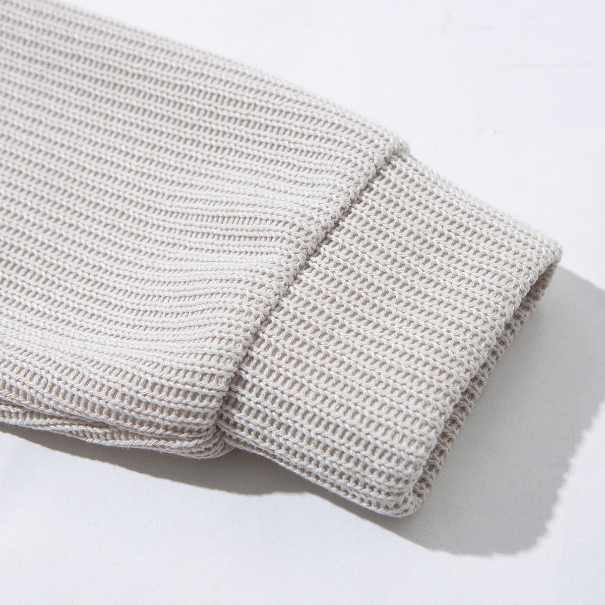 Close-up of the light beige cardigan's ribbed sleeve and wide cuff.