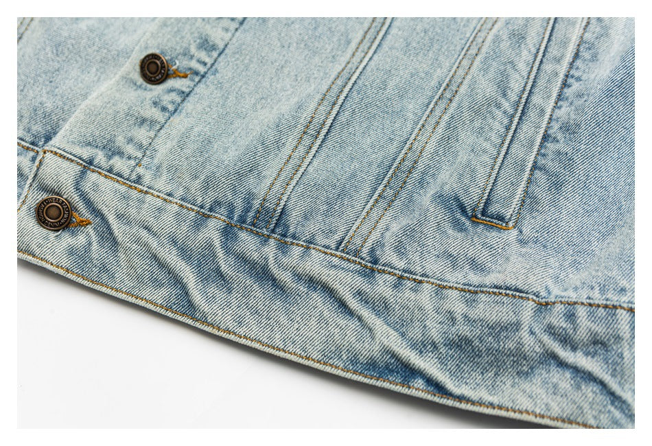 Close-up of the jacket's light blue denim hem, seams, belt loop, and metal buttons.