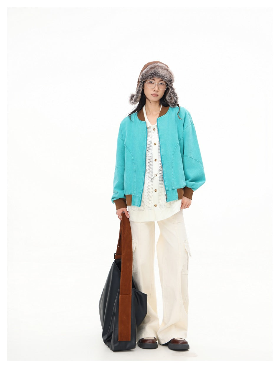 Model wearing open teal bomber jacket with brown trim over a white knit top, cream cargo pants and a fur-trim hat
