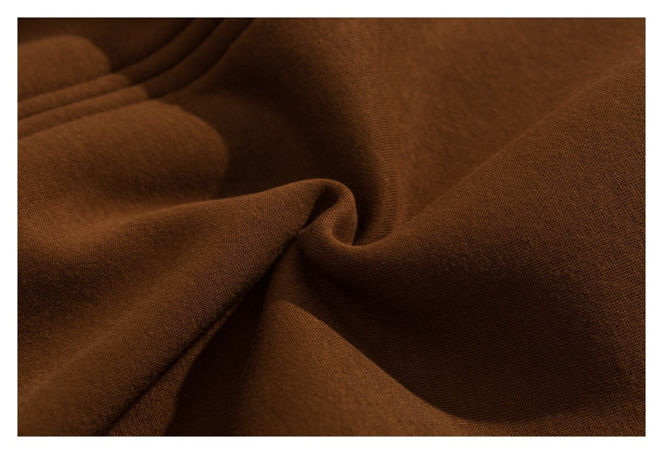 Close-up of smooth brown fabric draped into folds, showing its fine surface texture.