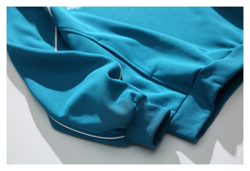 Close-up of the teal sweatshirt's sleeve, ribbed cuff, and white piping along the seam.