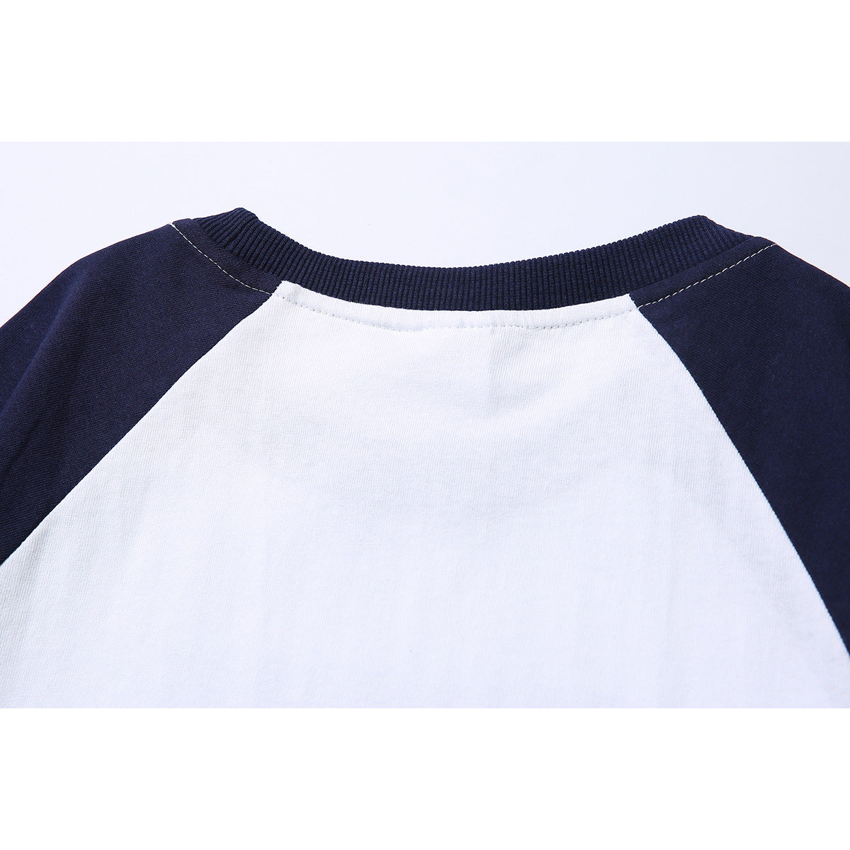 Close-up of the back neckline of a white-and-navy raglan T-shirt with a ribbed navy collar.