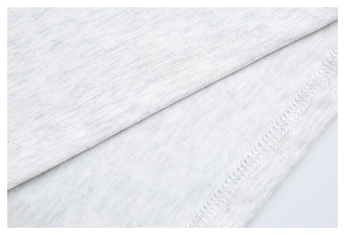 Close-up of a folded garment edge showing the hem stitching and overlocked seam on white heathered knit.