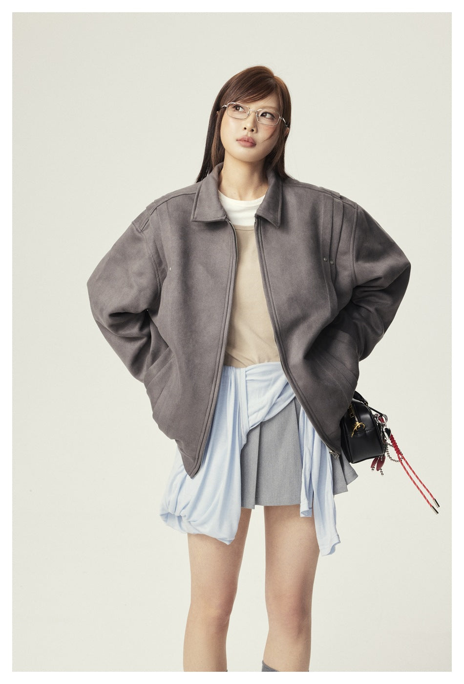 Model wearing an oversized gray zip jacket with a beige top and gray skirt.